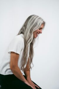 Mature woman with long silver hair laughing