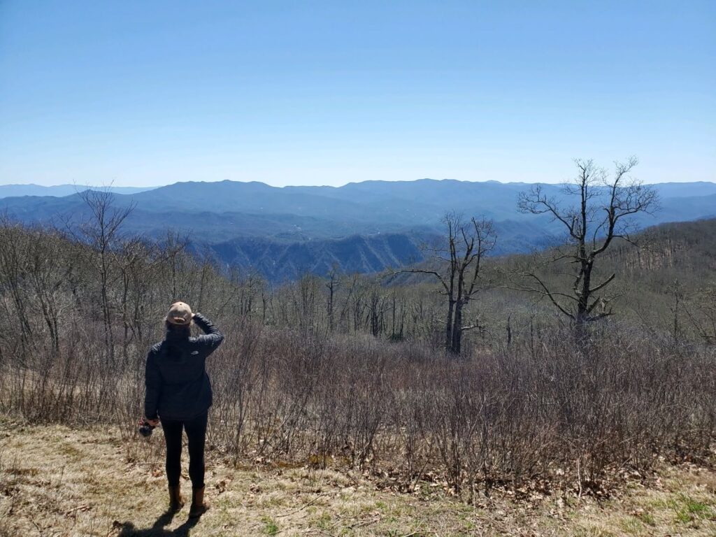Woman standing on mountain trail looking at Blue Ridge mountains
