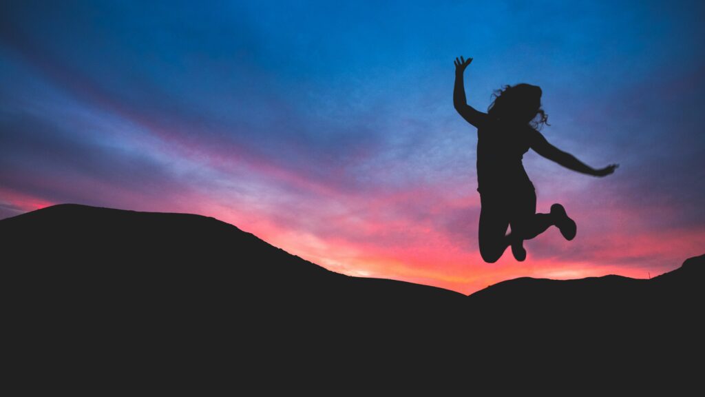 Woman silhouette jumping at sunset