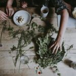 Women working with fresh herbs at wooden table